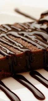 A rich chocolate brownie drizzled with syrup on a plate.