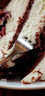 Slice of chocolate cake with cream filling and fork on plate.