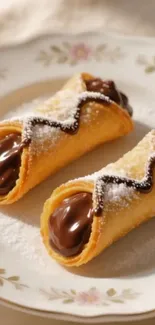 Two chocolate-filled cannoli on a floral plate.