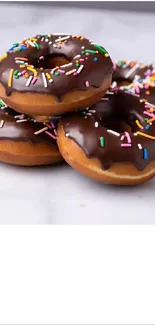 Stack of chocolate donuts with colorful sprinkles.