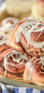 Stack of cinnamon rolls with icing on parchment.