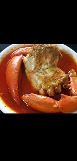 Vibrant crab dish with red sauce in a white bowl.