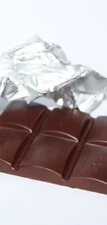 Dark chocolate bar partially unwrapped in foil.