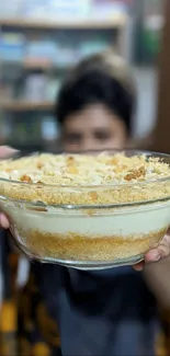 A close-up of a delicious dessert in a glass bowl, held towards the camera.