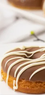 Chocolate donut with white icing on plate with coffee and flowers.
