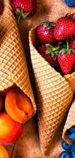 Waffle cones filled with strawberries and blueberries on wooden surface.