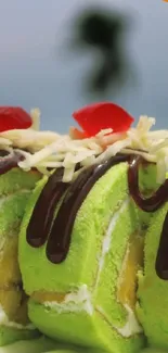 Close-up of green cake roll with chocolate drizzle and cherries.