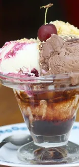 Ice cream sundae with chocolate, vanilla, and cherry on wooden table.