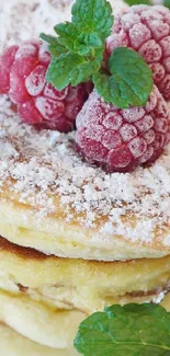 Fluffy pancakes with raspberries and mint on a white plate.