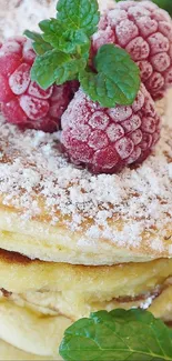Fluffy pancakes with raspberries and mint leaves on a white plate.