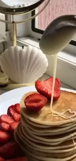 Stack of pancakes with strawberries and cream drizzle.