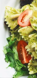 Close-up of pesto pasta with fresh greens and tomatoes.