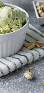 Pistachio ice cream in a white bowl with scattered pistachios.
