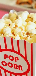 Box of freshly popped popcorn in a red and white striped container.