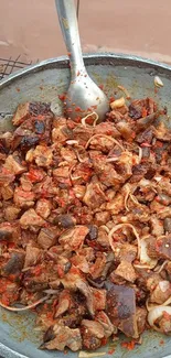 Spicy meat mix in a cooking pan with a metal spoon.