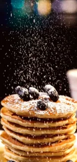 Stack of pancakes with berries and sugar dusting.