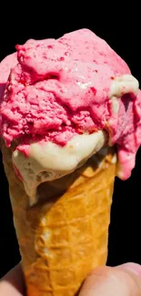 Strawberry ice cream cone against black background.