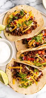 Taco spread with toppings and lime wedges on a marble background.