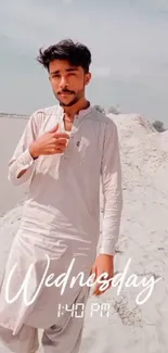 A man standing in a sunlit desert wearing traditional attire, with 'Wednesday 1:40 PM' overlay.