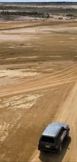 Cars driving on a deserted sandy road under a vast sky.