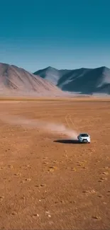 A car travels through a vast desert with mountains under a clear blue sky.