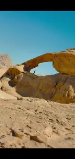 Desert arch landscape with blue sky and sandy terrain.