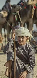 Young boy with camels in desert landscape.