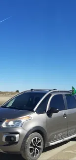 Car driving on a sandy desert under a clear blue sky.