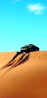 Vehicle climbing a desert dune under clear sky.