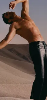 Man posing in the desert with sand dunes and stylish black pants.