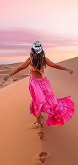 Woman in pink dress walking on desert dunes during sunset.