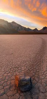 Rugged desert landscape with a sunset sky and distant mountains.