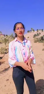 Woman in colorful shirt in sunny desert landscape.