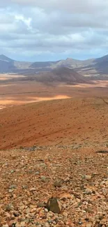 Vast desert landscape with distant mountains and a rocky foreground.