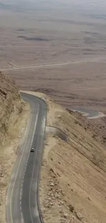 Winding road through vast desert landscape under clear sky.