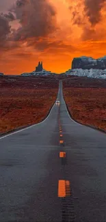 Dramatic desert road leading to horizon at sunset with vivid orange sky.