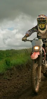 Rider on dirt bike racing through lush, green trails beneath a cloudy sky.