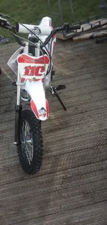 A dirt bike parked on a wooden deck outdoors.