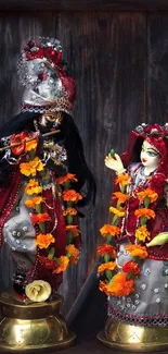 Divine couple statue on wooden background with colorful garlands.