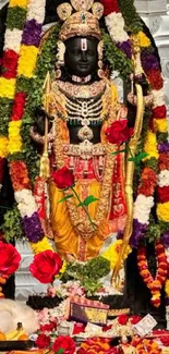 Divine deity adorned with colorful garlands and roses set in a temple background.