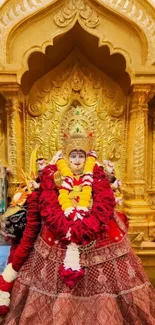 Golden temple deity adorned with flowers.