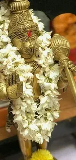 Golden Hanuman statue adorned with flowers, perfect for mobile wallpaper.