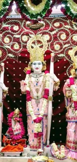 Divine trio of idols in vibrant attire set against a maroon background.