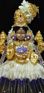 Indian deity statue with golden attire and intricate details on black background.