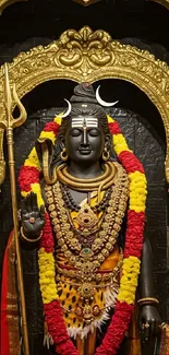 Statue of Lord Shiva adorned in gold and floral garlands.