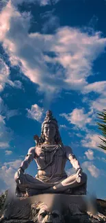 Statue of Lord Shiva against a blue sky with clouds, exuding serenity.