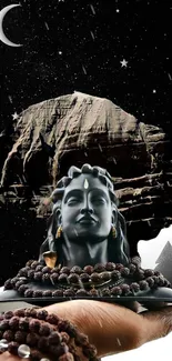 Shiva statue against a starry night sky, held in a hand.