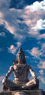 Serene Shiva statue under a vivid blue sky with clouds.