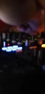 Close-up of DJ mixer with glowing lights in a dark setting.