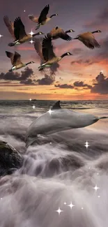 A dolphin jumps through ocean waves below birds at a vibrant sunset sky.